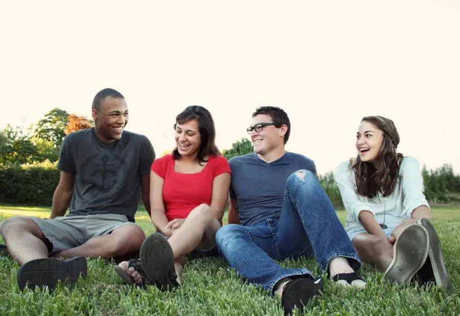 Mujeres Y Hombres Sonrientes Sentados Sobre La Hierba Verde