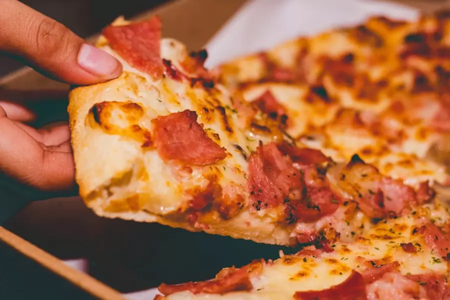 Foto En Primer Plano De Una Persona Sosteniendo Una Pizza