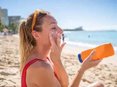una-mujer-aplicandose-protector-solar-facial en la playa/