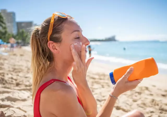 una-mujer-aplicandose-protector-solar-facial en la playa/