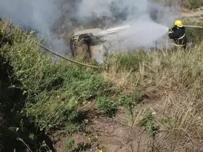 Los bomberos tratan de apagar el incendio del auto, con las dos v�ctimas fatales en su interior. (Foto: gentileza El Diario)