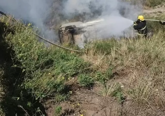 Los bomberos tratan de apagar el incendio del auto, con las dos v�ctimas fatales en su interior. (Foto: gentileza El Diario)