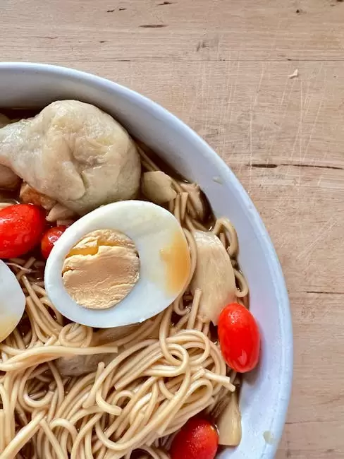 Primer plano de un plato de fideos con huevos, tomates cherry y champi�ones.