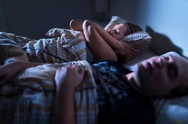 Mujer que no puede dormir por los ronquidos.